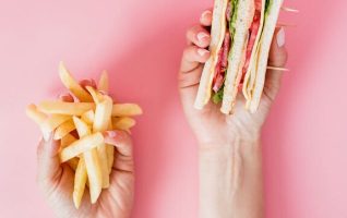 Hands holding fries and a sandwich.