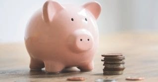 A piggy bank with coins next to it.