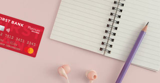 First Bank Secured Mastercard next to a notebook.