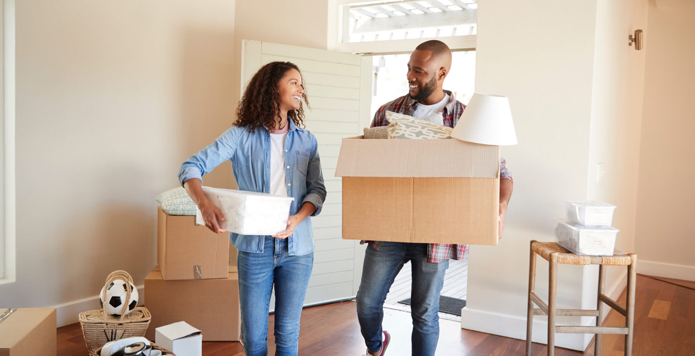 Couple smiling carring moving boxes into new house
