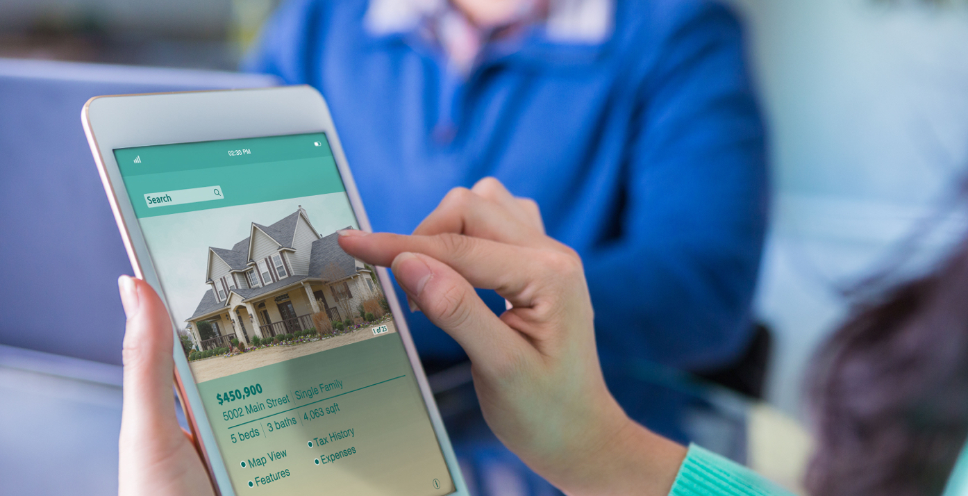 Hand pointing at iPad with home buying app on screen