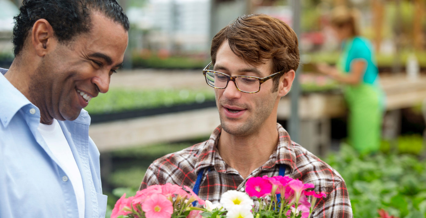 Customer being shown flowers by an employee in a greenhouse