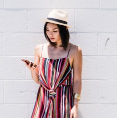 Woman checks smart phone by wall.
