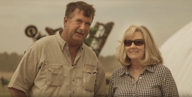 The Hagler's standing in front of farm equipment