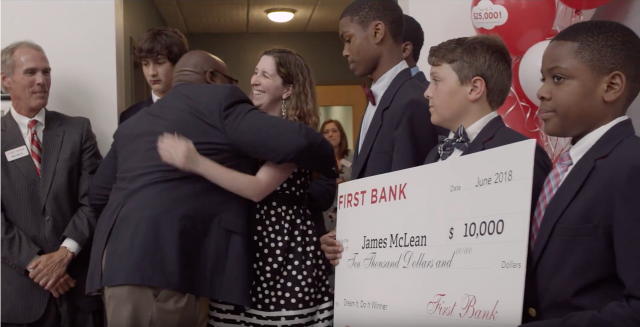 boys wearing suits holding large check