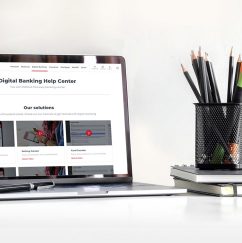 Laptop showing help center screen sitting on desktop next to pencil holder and notebook