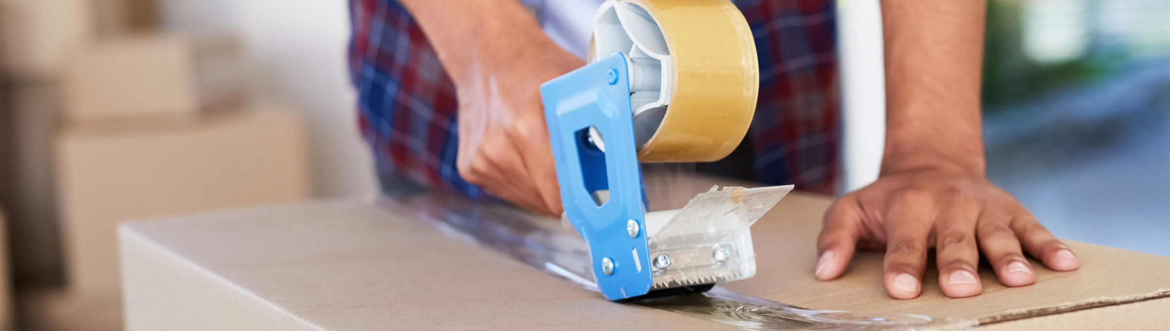 Man's hands with packing tape on packing box