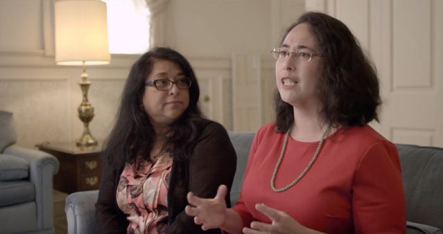 Two women sitting on couch, being interviewed.