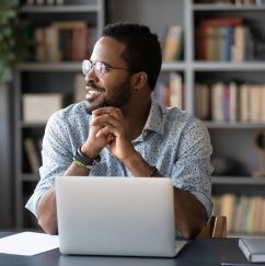 Man sitting at desk, smiling, looking out window