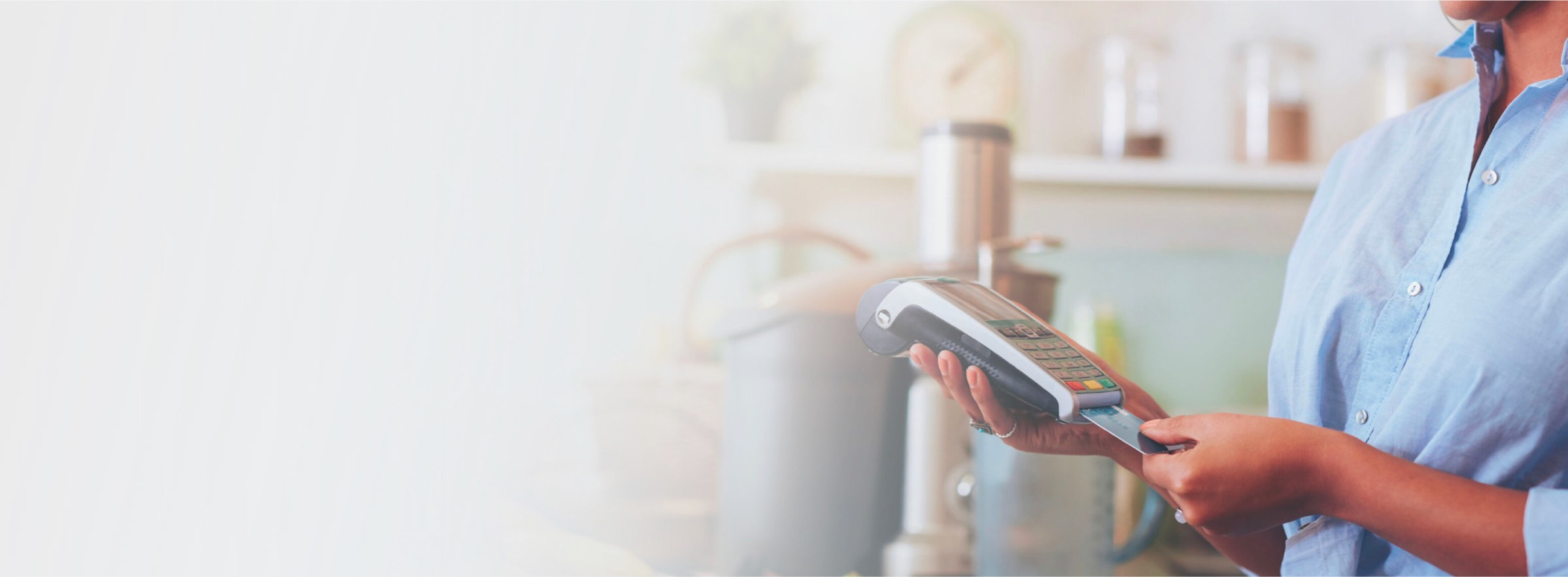 Business owner holding a First Bank Payment Processing terminal accepting a credit card.