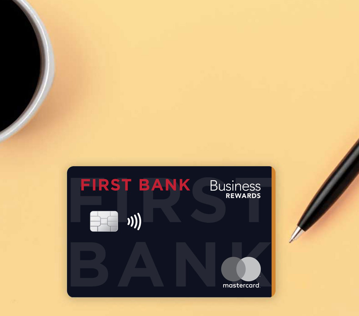 First Bank business credit card on yellow background with pen and coffee cup