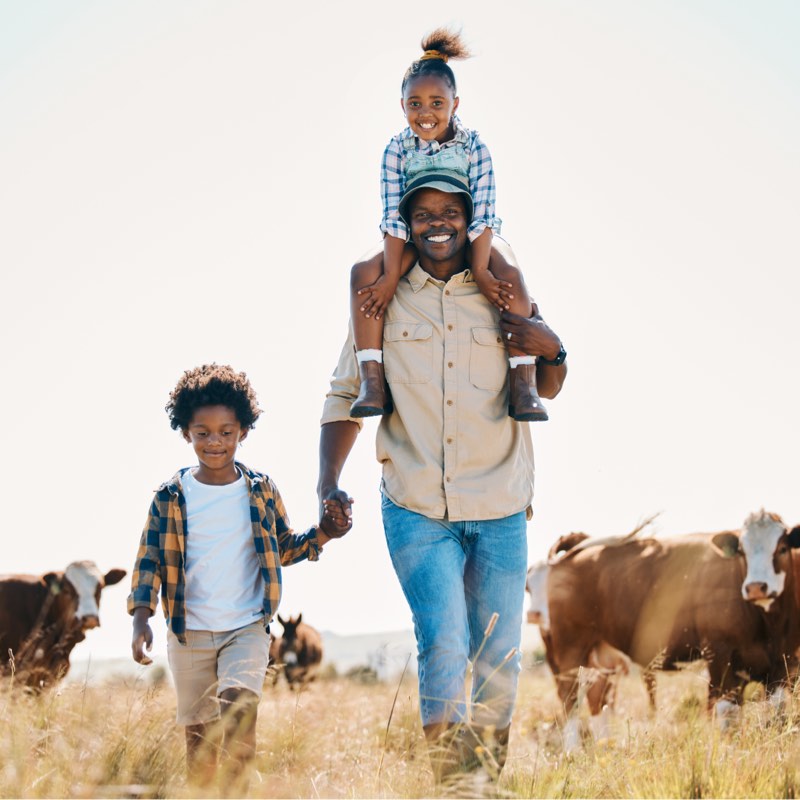 Dad with kid on his shoulders walking through a field.