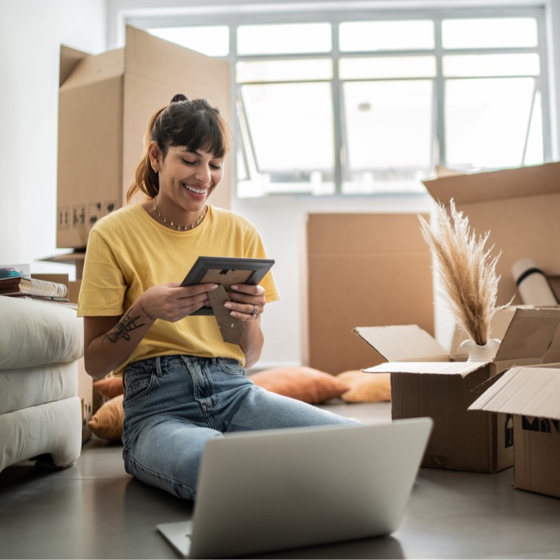 Woman moving into a new house and unpacking a picture frame.