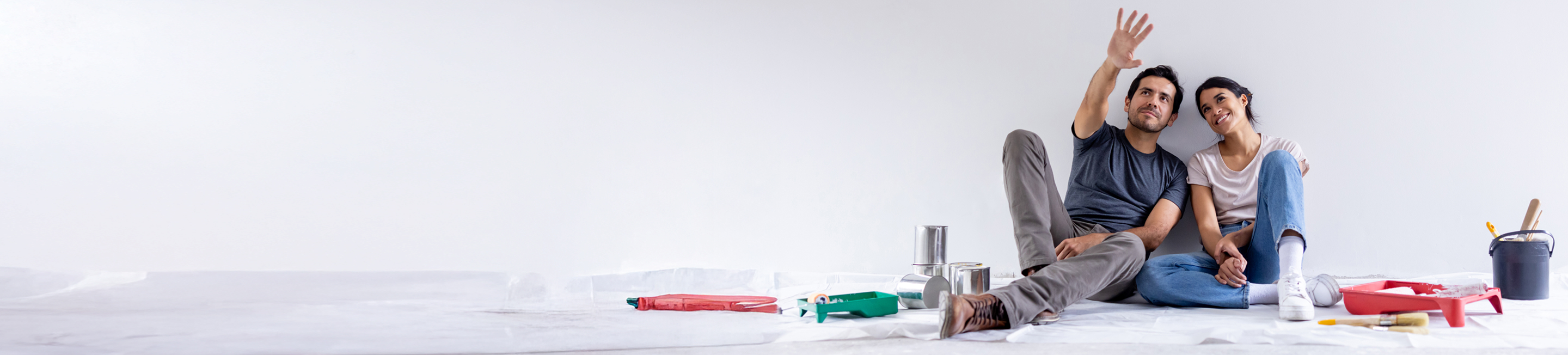 Couple sitting on the floor planning how they want to paint a room.